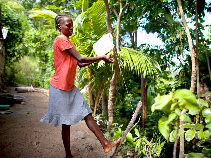 Miscaden Ronel, washes her hands at a simple hand washing station set up at her home.