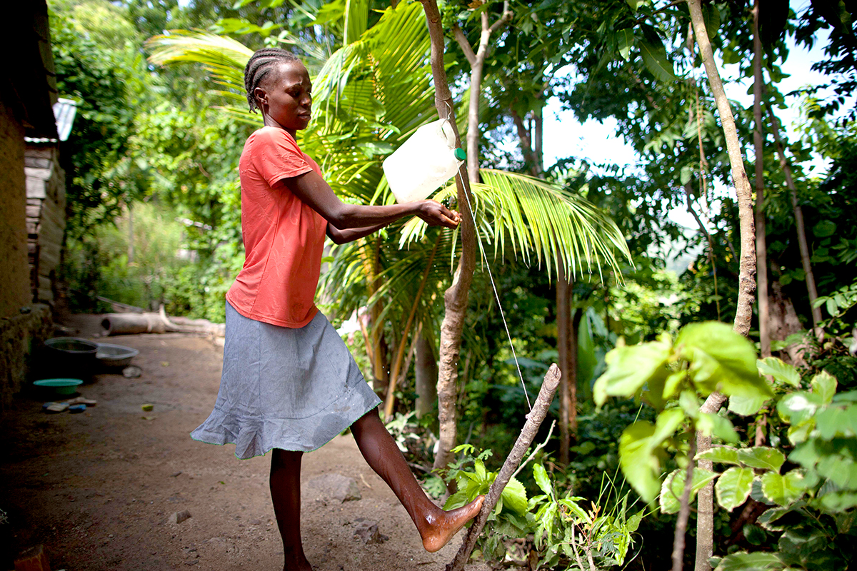 Miscaden Ronel, washes her hands at a simple hand washing station set up at her home.